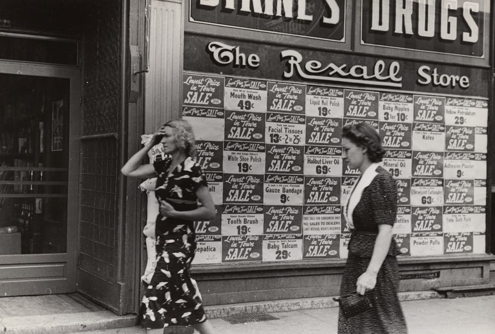 Photographie en niveaux de gris de deux femmes marchant près d’un bâtiment