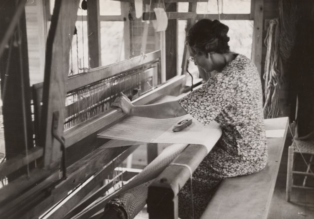 Mujer sentada usando la máquina de tejer