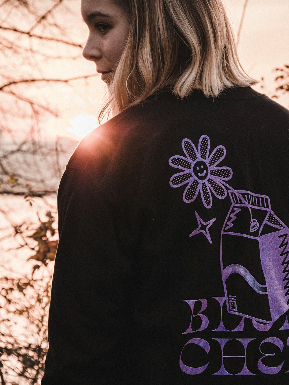 woman wearing black and purple printed sweatshirt standing while facing back and glancing her left side