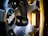 Close-up view of a car wheel with a metallic finish featuring a BBS logo in the center. The image highlights the detailed design of the wheel spokes and the reflective surface, with hints of surrounding light casting a yellowish glow.