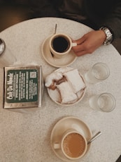 black coffee in white ceramic mug near sliced cake, water in drinking glass, and clear condiment shaker on table