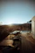 brown wooden armless chairs on balcony viewing field under blue and white sky