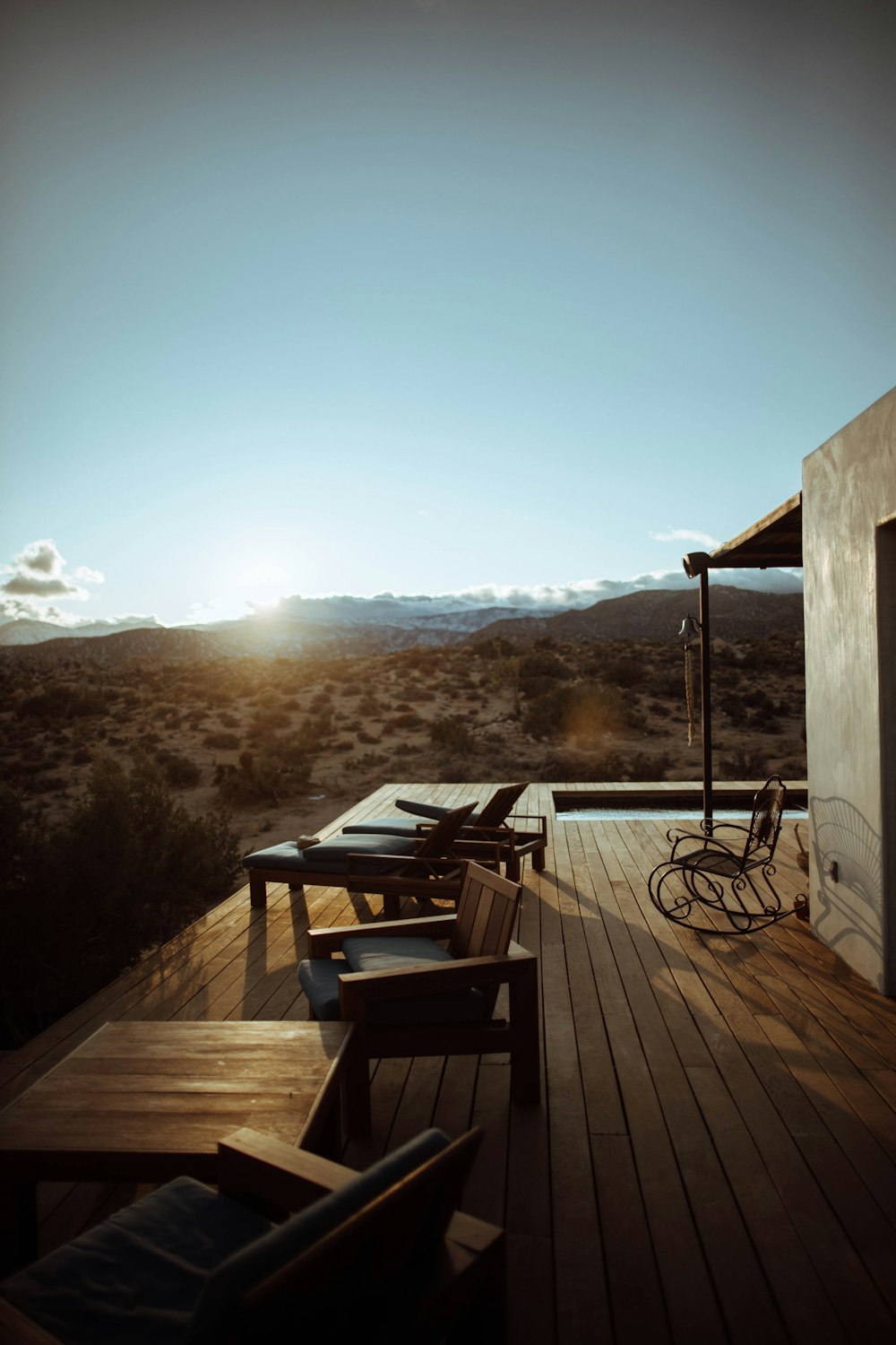 brown wooden armless chairs on balcony viewing field under blue and white sky