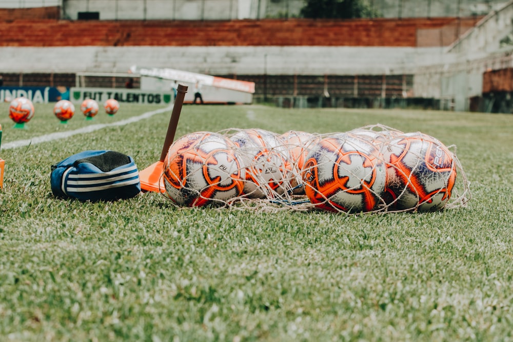 Palloni da calcio bianchi e arancioni e rete sul campo