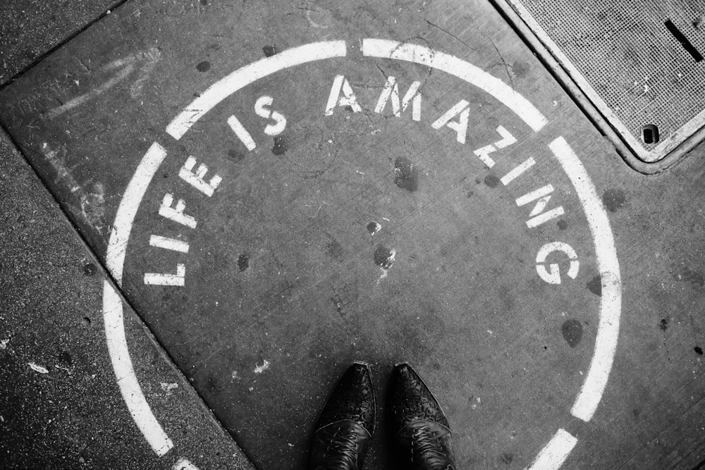 person wearing leather shoes stepping on Life is Amazing circle texts