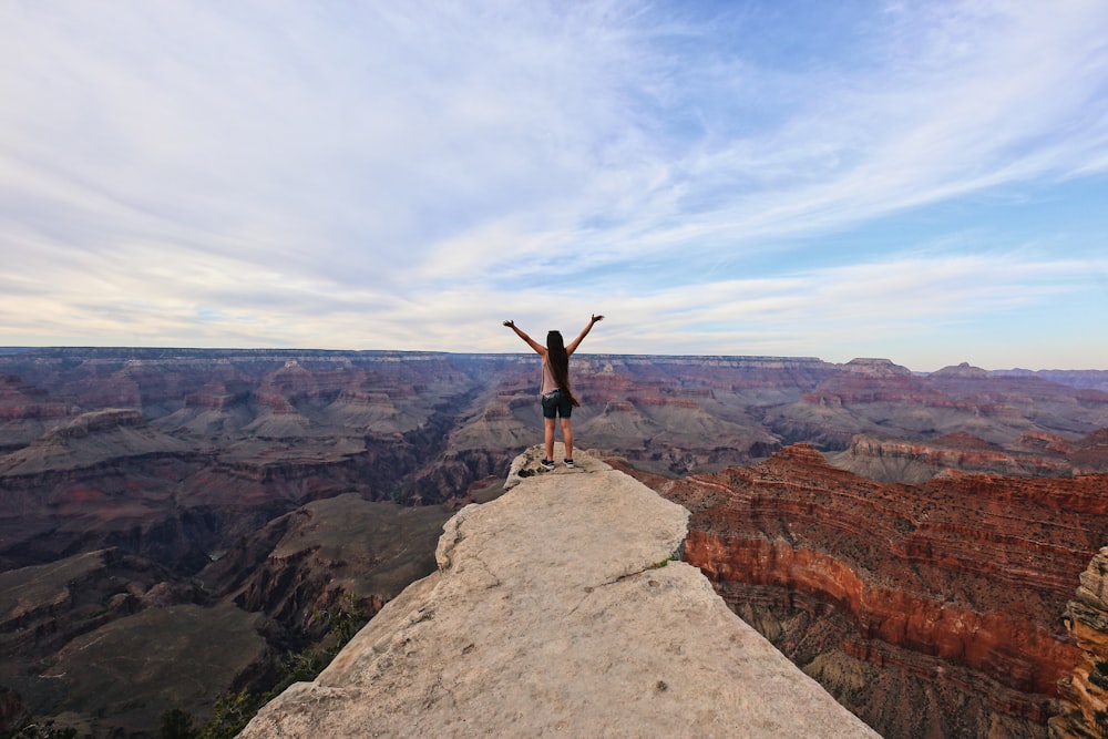 woman standing on cliff's edge during daytime