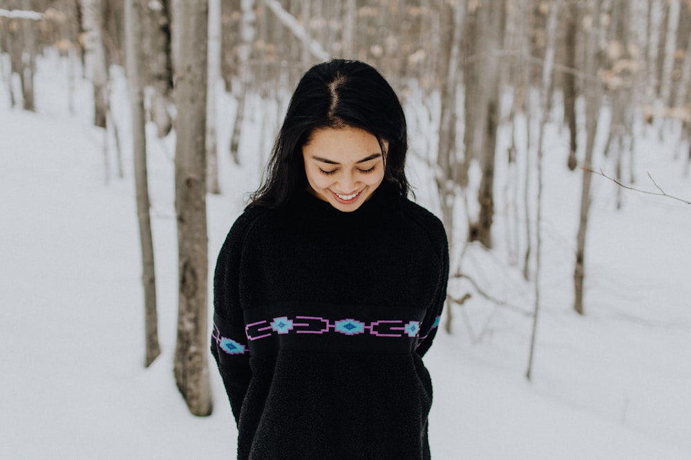 a woman standing in the snow in front of trees