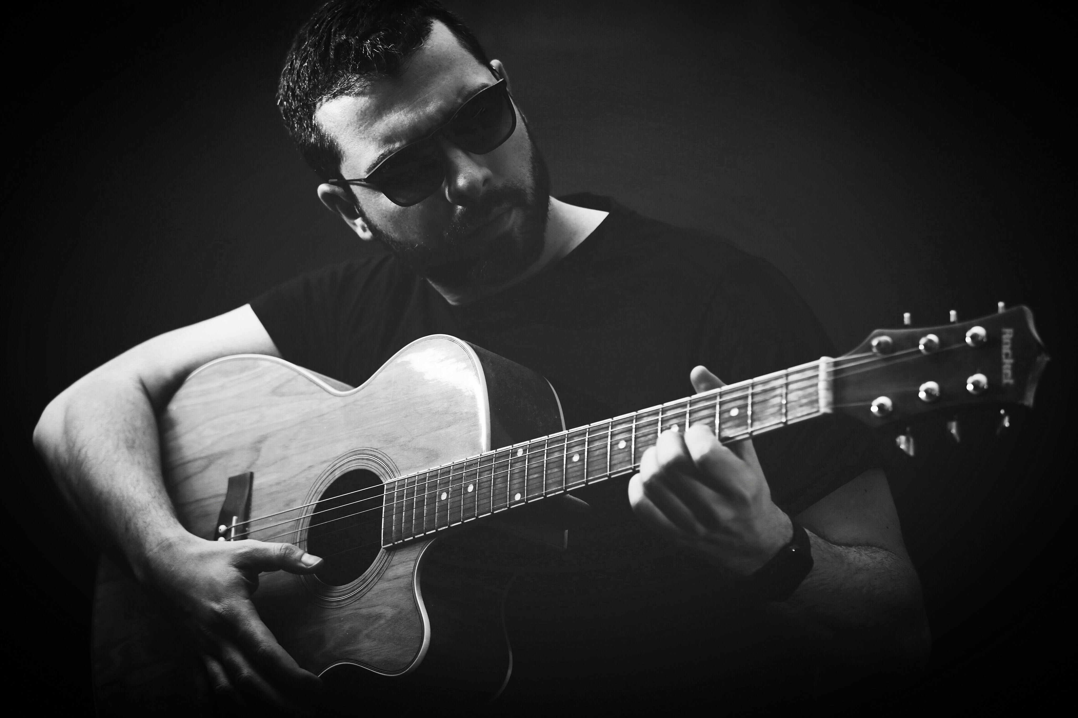 grayscale photo of man playing guitar