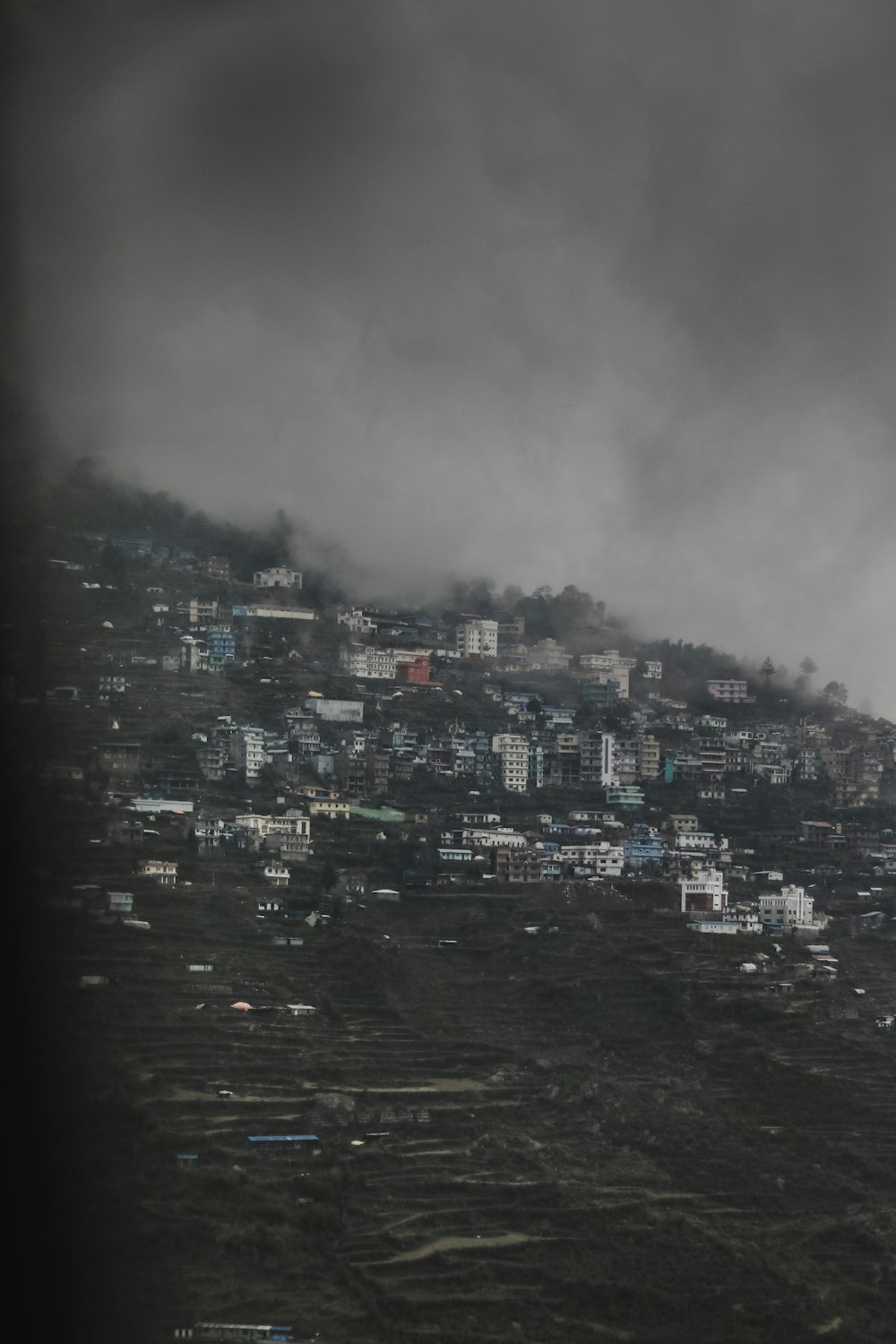 Photographie en niveaux de gris de bâtiments sur la montagne pendant la journée