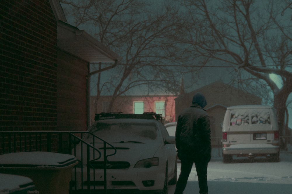 man standing beside vehicles covered by snow