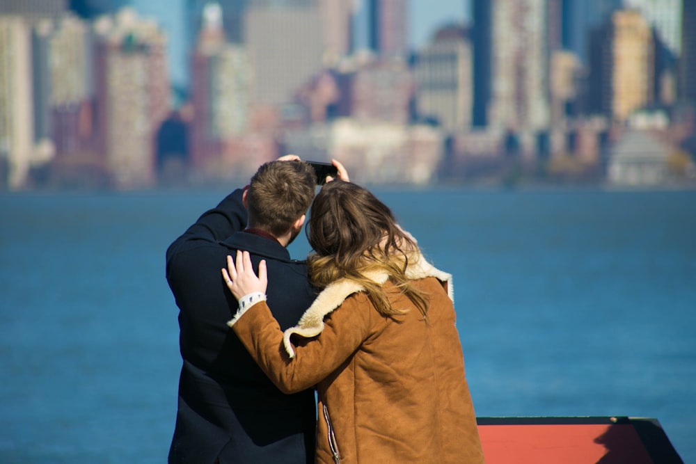 man and woman taking a photo near body of water