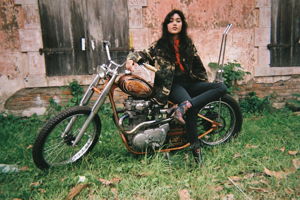 Mujer sentada en motocicleta de turismo cerca de la casa