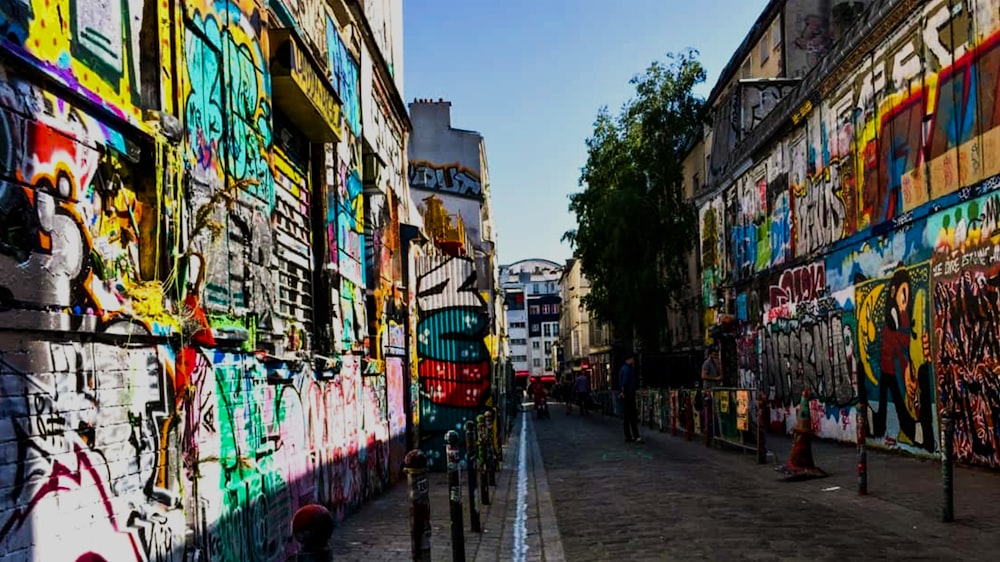 people walking on sidewalk near building with graffiti