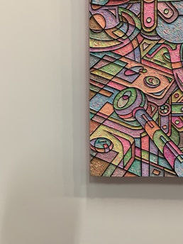 An abstract artwork featuring a multitude of geometric shapes and forms, outlined in black and filled with a spectrum of pastel colors. The textured surface adds depth and dimension, with swirling patterns and intersecting lines creating a sense of movement within the composition.