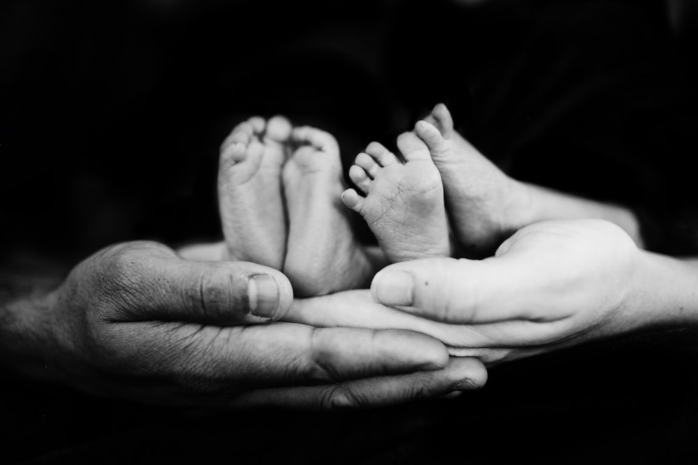 Foto en escala de grises de una persona sosteniendo a un bebé