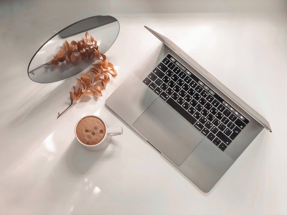 MacBook al lado de la taza