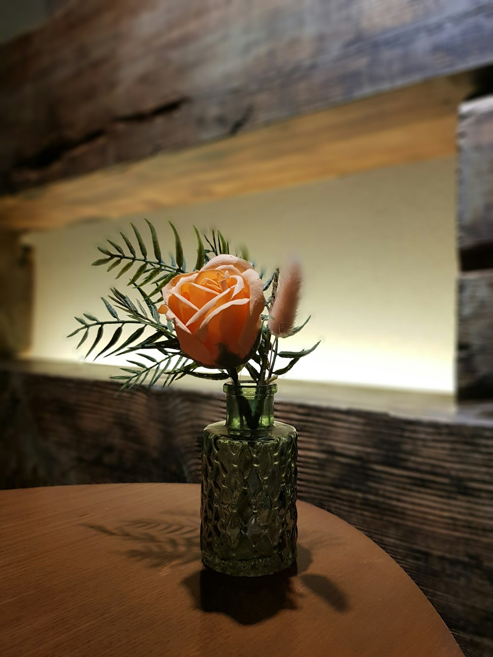 orange Rose flower in glass vase on table