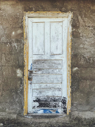 A rustic door with peeling paint, evoking stories of the past.