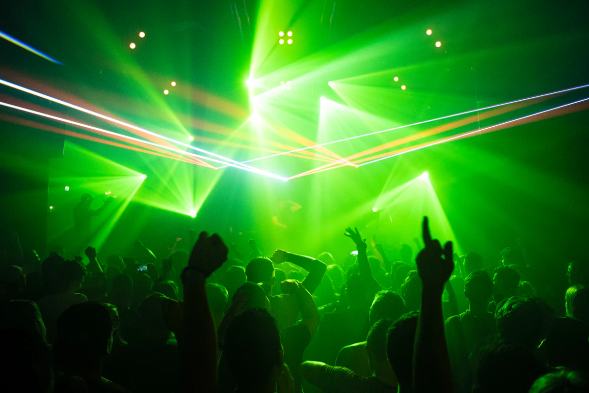 People dancing on a club floor lit by green laser lights