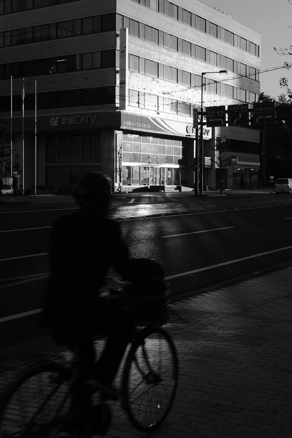grayscale photo of person riding bicycle on sidewalk