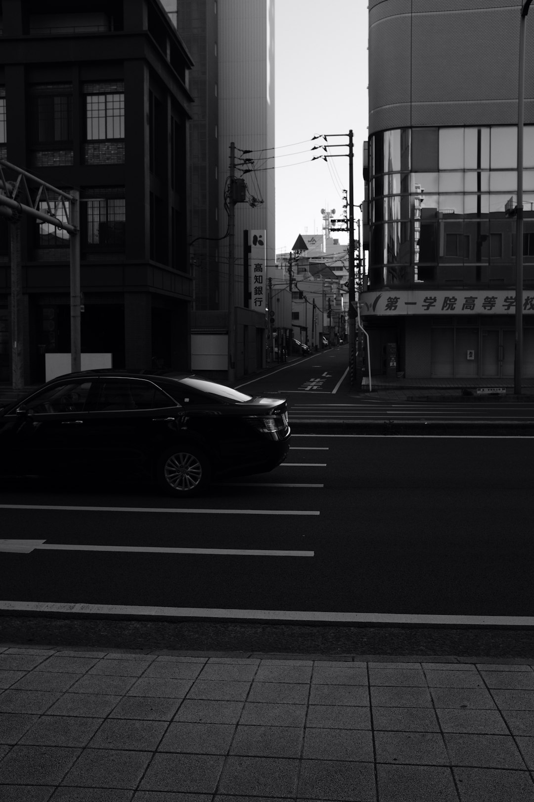 grayscale photo of sedan travelling on road