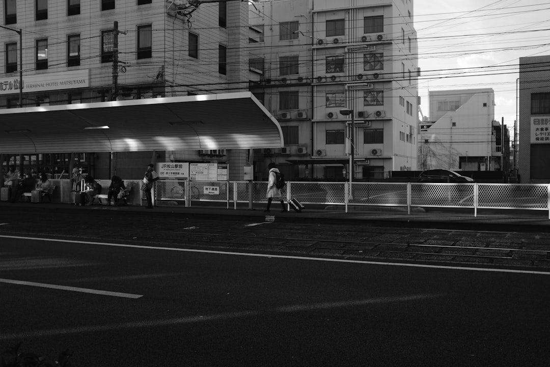 people at the waiting shed in grayscale photo