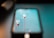 Two light bulbs with red bases are reflected on a smartphone screen. They are set against a backdrop with a turquoise hue.