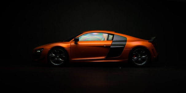 Sleek supercar outline with wing curves and fiery orange accents against a dark background.