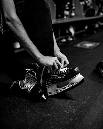 A young player lacing up a pair of ice hockey skates before hitting the ice