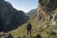 An adventurous hiker standing on a cliff overlooking a valley.
