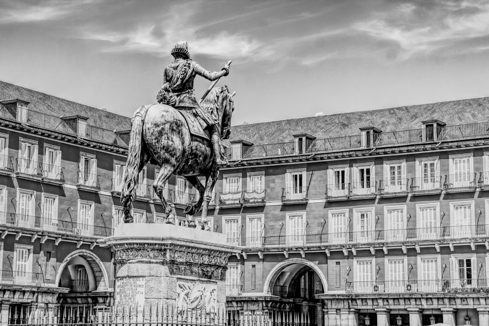 man riding horse statue under cloudy sky
