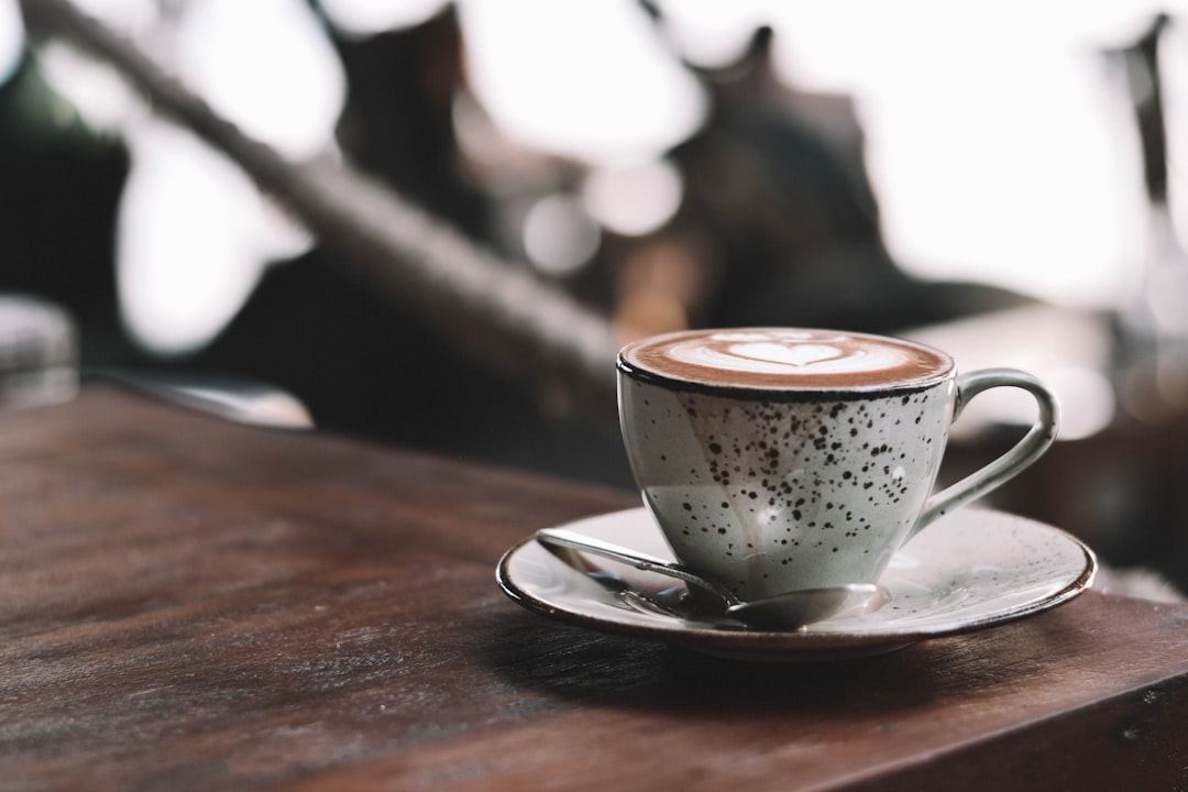 selective focus photography of full white ceramic mug on saucer on brown wooden table