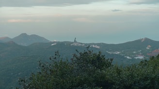 A serene Irish landscape featuring rolling hills and a statue of Saint Patrick in the distance.