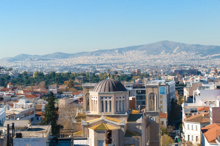 Athens rooftops and a church dome, the city running back to the mountains.