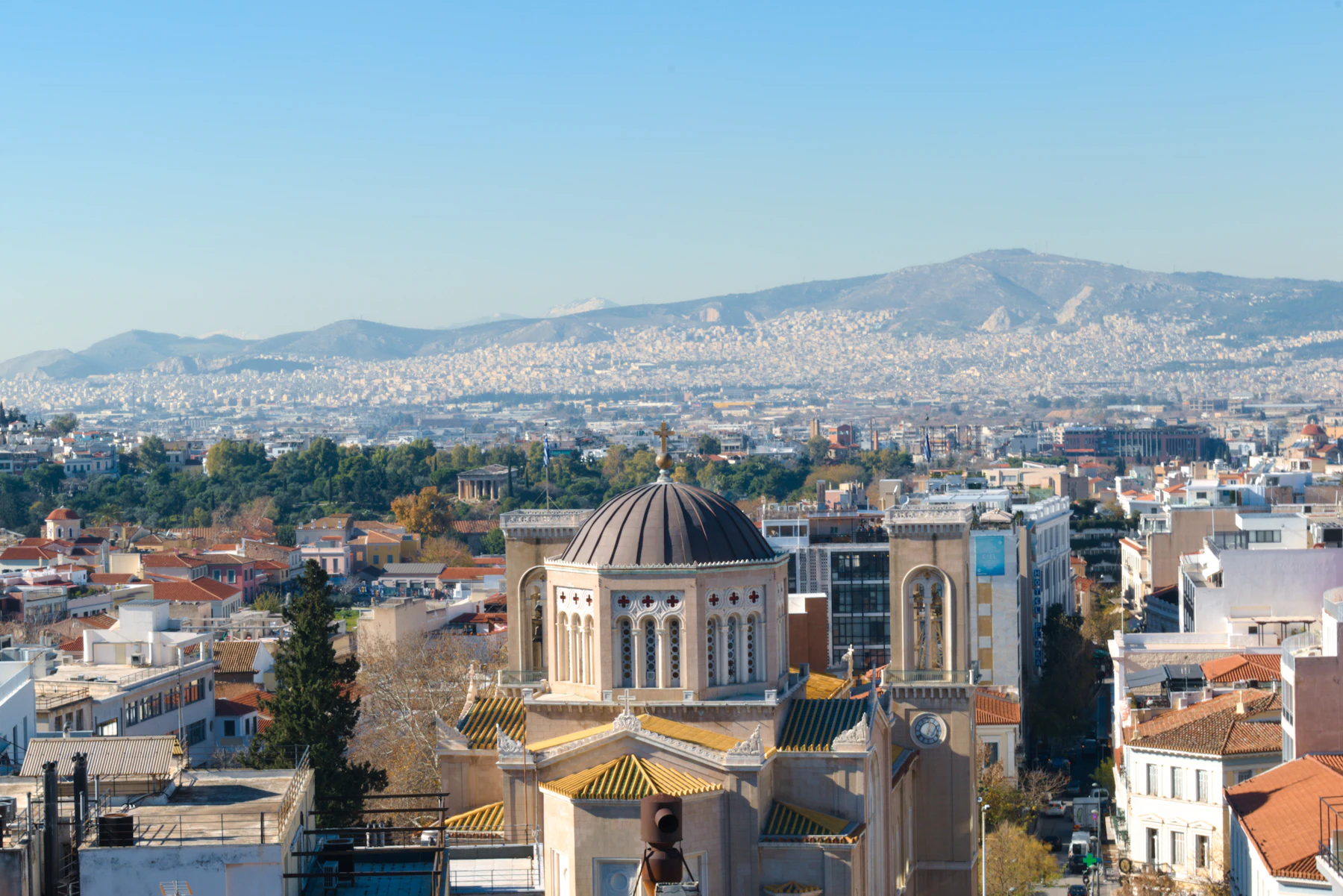 Athens rooftops and a church dome, the city running back to the mountains.