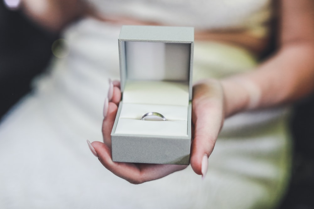 selective focus photography of woman holding box of ring