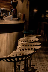 Rustic industrial iron bar stool with a worn metal finish sitting by a wooden counter