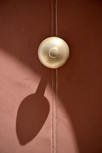 A polished brass door knob logo with a subtle shadow effect.