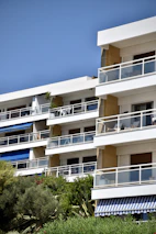 Finished apartment building exterior with balconies and greenery around.