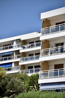 Modern residential apartment building with balconies surrounded by greenery.