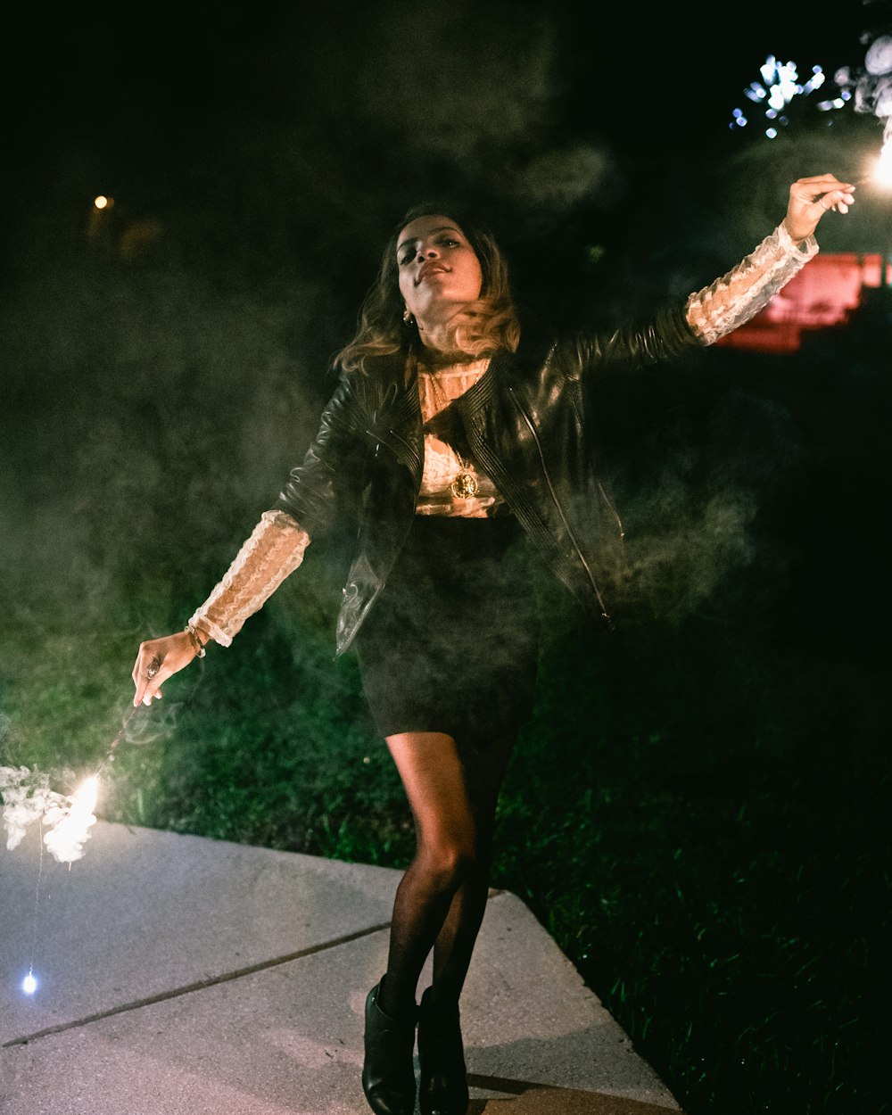 standing woman hands holding sparklers at night