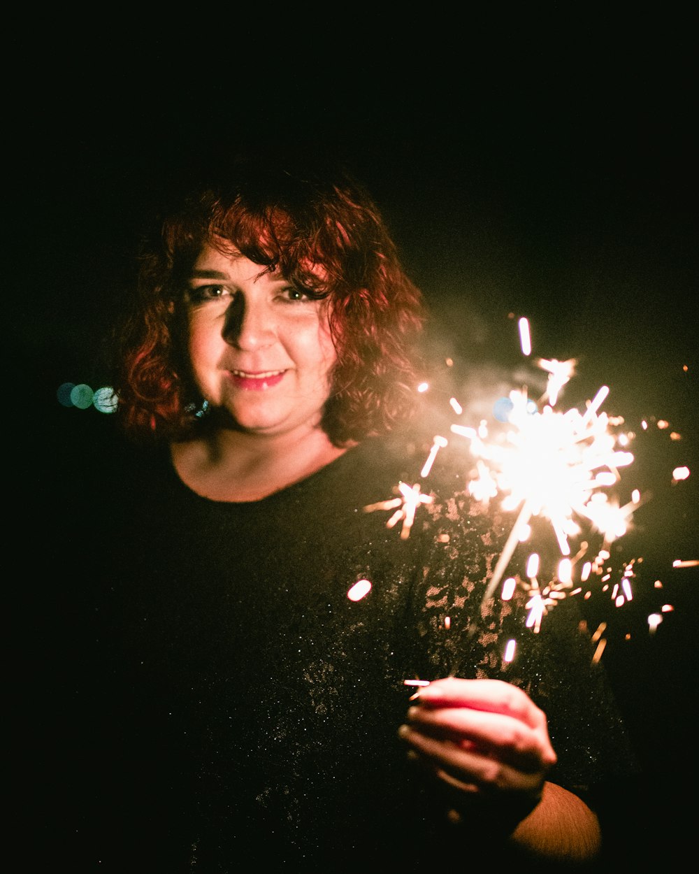 selective focus photography of smiling woman holding lit sparkler