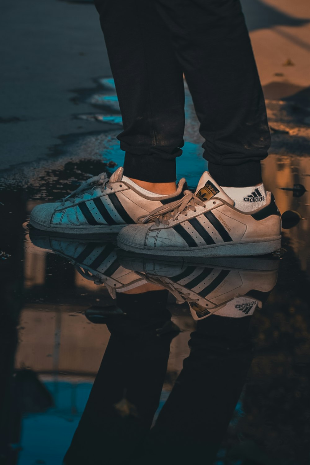 standing person wearing white adidas low-top sneakers reflecting on water  puddle photo – Free Image on Unsplash