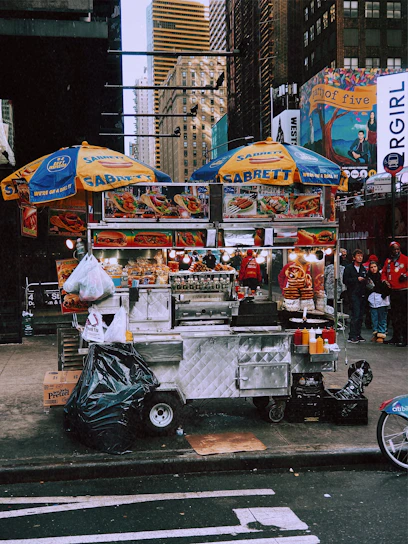 A vibrant street vendor cart with Sabrett hotdogs sizzling under a bright New York City skyline.