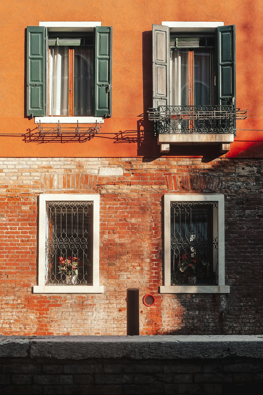 a red brick building with green shutters and windows