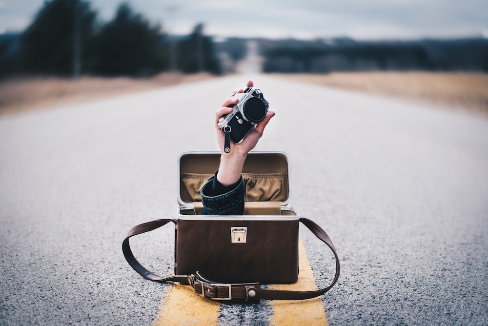 black and gray camera and bag on road
