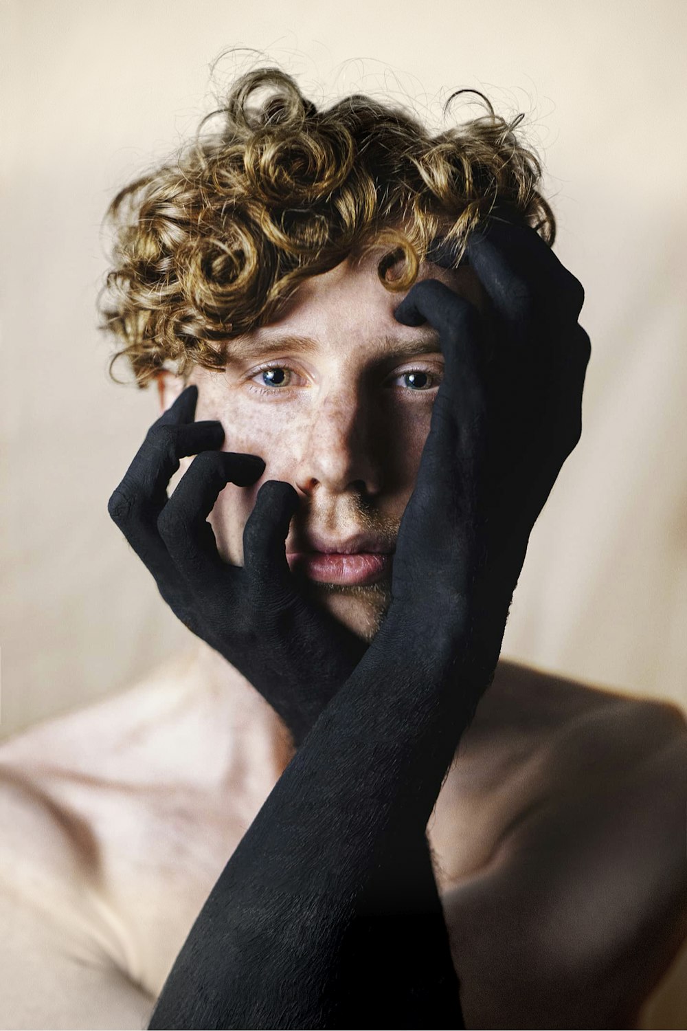 topless man touching his face with black paint