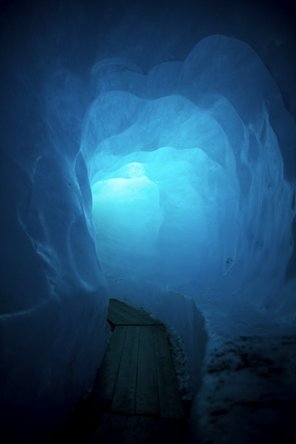 a wooden bench sitting inside of a blue ice cave