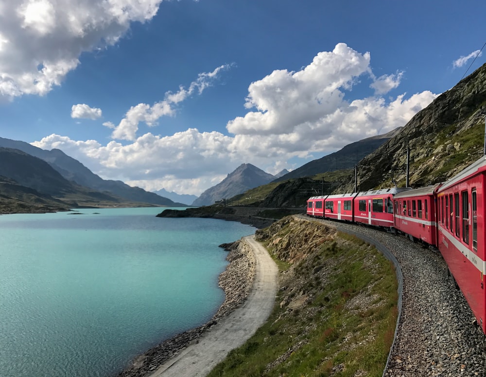 red train travelling near body of water