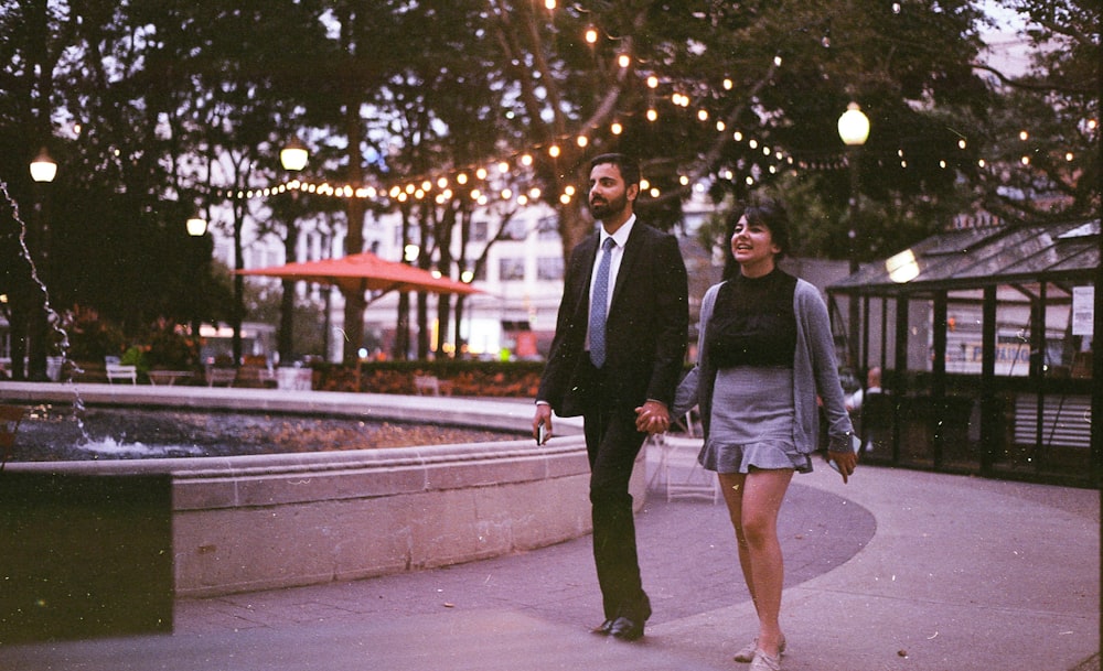 man and woman walking near fountain